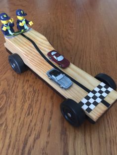 a toy car made out of wood with two people on the front and back wheels