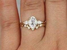 a woman's hand with a diamond ring on top of her finger and the other hand holding an engagement ring