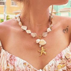 Embrace the essence of the ocean with our Shell Necklace, adorned with a charming collection of multi ocean-inspired charms. This necklace features delicate starfish, a lustrous freshwater pearl, and a detailed seashell, each representing the beauty of the sea. Crafted with a tarnish-free and waterproof finish, this necklace is designed to maintain its elegance and shine, even with regular wear. Perfect for adding a touch of coastal charm to your summer wardrobe, this elegant piece is a must-have accessory. Whether you're strolling on the beach or enjoying a night out, the Shell Necklace is versatile enough to complement any outfit. Details: -Necklace Length: 45 cm + 5 cm Extension. -Pendant Measurements: Starfish 3.28 cm Approx. -Metal: 18k Gold Plated over Stainless Steel -Stone: Shell, Ocean-inspired Jewelry With Star Charm, Summer Starfish Charm Star Necklace, Star Charm Necklaces For Beach, Star Charm Necklace For Beach, Beach Star Charm Necklace, Bohemian Starfish Necklace For Gifts, Bohemian Starfish Necklace For Gift, Summer Star Charm Necklace As Gift, Summer Star Charm Necklace Gift