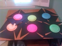 the table is made out of paper plates with colored circles on them, and sits in front of a window