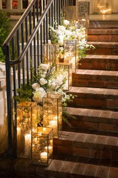 candles are lit on the steps leading up to an entrance with flowers and greenery