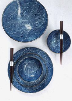 three blue plates and two chopsticks on a white surface