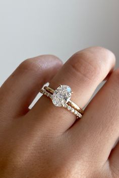 a woman's hand with a diamond ring on top of her finger and an engagement band