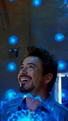 a man laughing while looking up at blue lights