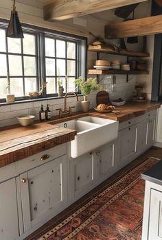 a kitchen with white cabinets and wooden counter tops, an area rug on the floor