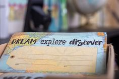 a piece of paper with the words dream explore discovery written on it sitting on a desk