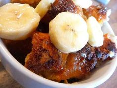 a bowl filled with bananas and other toppings on top of a wooden table next to a fork