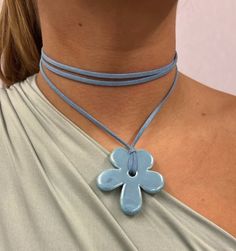 a woman wearing a blue necklace with a flower pendant on it's back neck