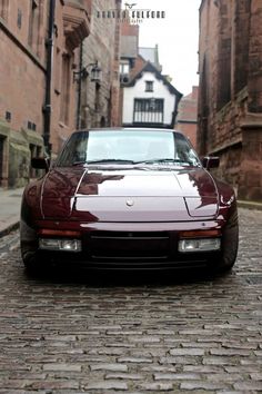 a red sports car parked on the side of a brick road in an alleyway