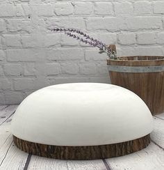 a white vase sitting on top of a wooden table next to a potted plant