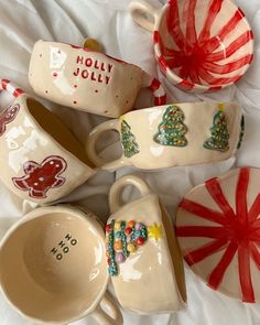 christmas themed ceramic dishes and cups on a white sheet with candy canes in the background