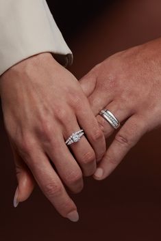 two people holding hands with wedding rings on their fingers and one is wearing a diamond ring