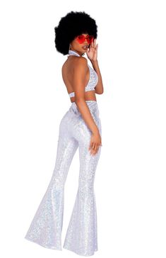 a woman with an afro is wearing white sequin pants and a halter top