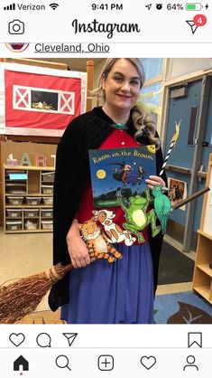 a woman is holding a book in her hand and smiling at the camera while standing in front of a classroom