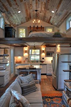 a living room filled with furniture next to a kitchen and dining area on top of a wooden floor