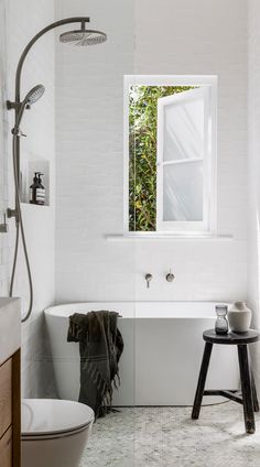 a white bathroom with a tub, toilet and window in it's center area