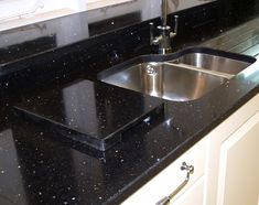 a black counter top with a stainless steel sink and faucet in the middle