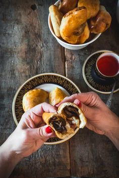 a person holding a pastry in front of some plates with pastries and tea on the table