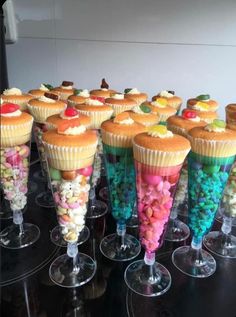 there are many cupcakes and candy in the cups on the table with each other