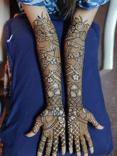 two hands with henna tattoos on them, one is showing the intricate pattern and the other has an elaborate design