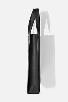 Our take on a classic piece, boasting sturdy construction and clean lines. Handcrafted in Montreal from our signature matte black pebbled cowhide, Tote is an everyday carryall with a flexible body and structured base. Its main compartment can fit up to a 16-inch laptop. Large exterior and small interior pockets are integrated for everyday essentials. + Width: 12.5in / 32 cm+ Height: 16.5in / 41 cm+ Depth: 3.5in / 9 cm+ Handle Drop: 9.5in / 24 cm Leather Bag Pattern, Minimal Classic, Oversized Tote, Convertible Bags, Black Pebbles, Montreal Canada, Purse Pouch, Mini Crossbody, Large Tote