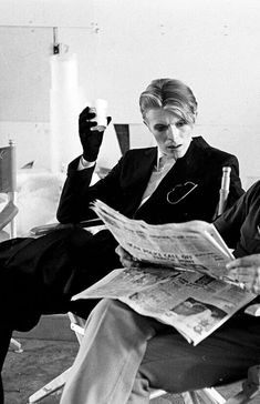 a man in a suit sitting down reading a newspaper