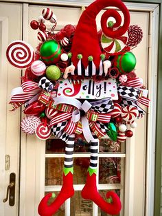 a christmas wreath with candy canes and elf feet hanging from it's front door