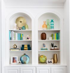 two white shelves with books and vases on them