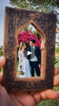 a person holding up a small mirror to take a photo with the bride and groom