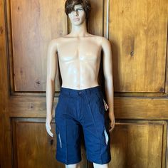 a male mannequin is posed in front of a wooden door wearing blue shorts