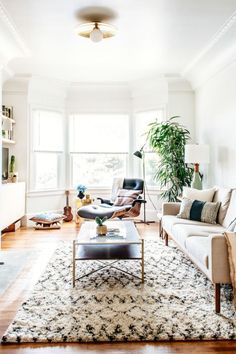 a living room filled with furniture and a large rug on top of a hard wood floor