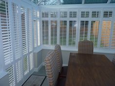 a dining room table and chairs with white shutters