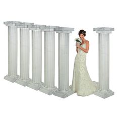 a woman in a wedding dress standing next to some white pillars and holding a bouquet