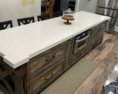 a kitchen island made out of wood and white counter tops with drawers on each side