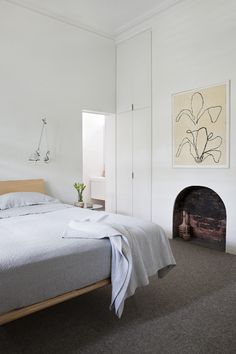 a bedroom with a bed, fireplace and painting on the wall