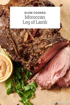 slow cooked moroccan leg of lamb on parchment paper with garnishes and sauce