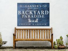 a wooden bench sitting in front of a white wall with a blue sign on it