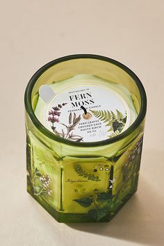 a glass jar filled with green leaves and flowers