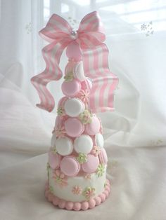 a pink and white christmas tree cake with buttons on the top, sitting on a table