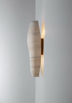 a light that is on the side of a white wall next to a vase with yellow lights in it