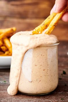 a person dipping some fries into a jar