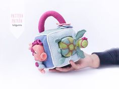 a hand holding a crocheted purse with an elephant and pig on the front