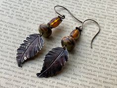 * Autumn! I pulled in several shades of amber in these beauties by pairing a beautiful amber Czech glass bead with the perfect polymer clay branch bead by Humblebeads. I then hammered leaf veins on a Vintaj blank component and then added several shades of patina.  * Earrings measure 3 inches  * Designed in Poestenkill NY * NOTE: Wearing in water or to the gym is not recommended  * NOTE:  As with most jewelry , do not force an adjustment if an earring becomes mis-aligned or stuck. Just give a gentle tug or wiggle and it will straighten out easily. Nickel-free Brown Earrings With Czech Glass, Nickel Free Brown Earrings With Czech Glass, Nickel-free Brown Czech Glass Earrings, Nickel-free Amber Czech Glass Earrings, Nickel-free Brown Czech Glass Jewelry, Brown Czech Glass Bead Earrings, Handmade Amber Earrings In Czech Glass, Nature-inspired Brown Earrings For Jewelry Making, Nickel-free Brown Beaded Earrings With Czech Glass