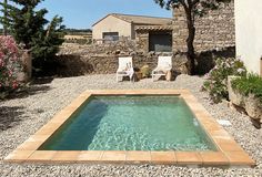 a small pool in the middle of a graveled area next to a stone building