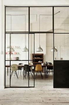 an empty room with chairs and tables in the center is seen through large glass windows