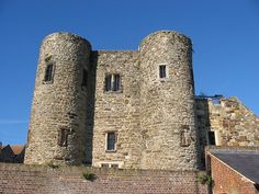 an old brick castle with two towers on the top and one at the bottom, against a blue sky