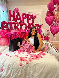 a woman sitting on top of a bed with pink balloons