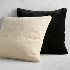 two black and white pillows sitting next to each other on top of a countertop