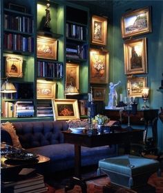 a living room filled with lots of furniture and bookshelves covered in framed pictures