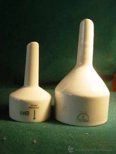 two white vases sitting next to each other on a green counter top, one is empty